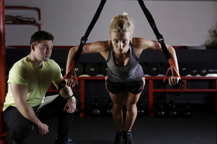 Woman using suspension training equipment.